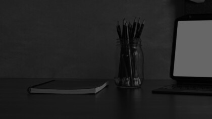 Desk with notebook, laptop and jar of pencils